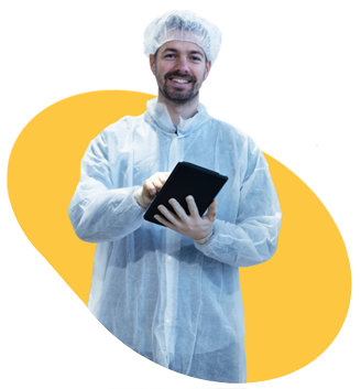 An inspector dressed in a white coat and hairnet, holding a tablet